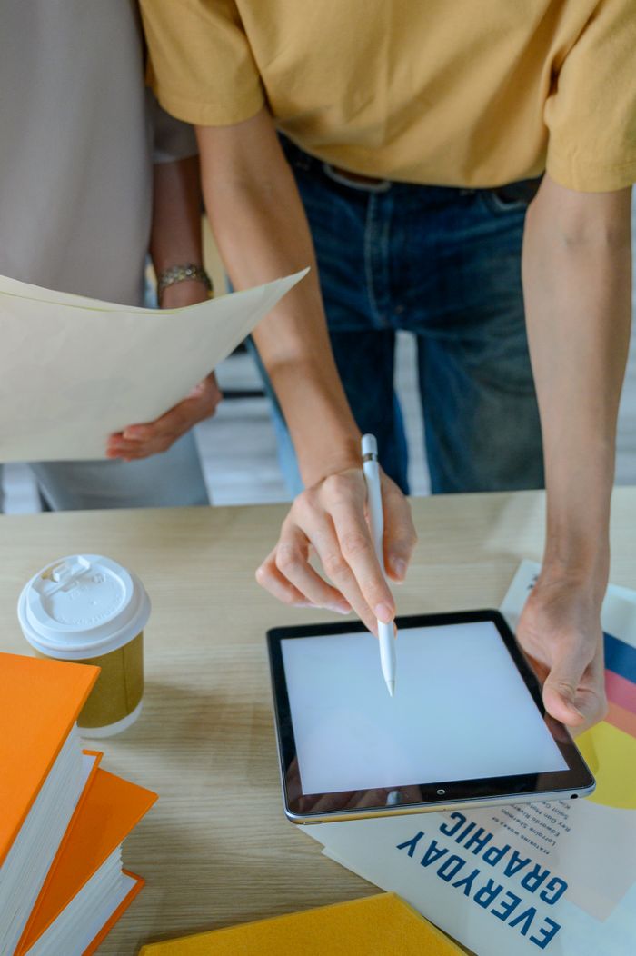 Two colleagues collaborate using a tablet in a modern office, focusing on teamwork and digital tools.